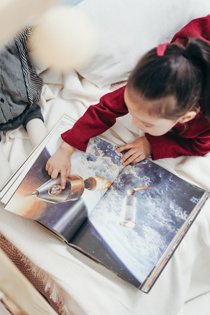 testimonial-img Young girl exploring a space-themed book indoors, capturing curiosity and enjoyment.